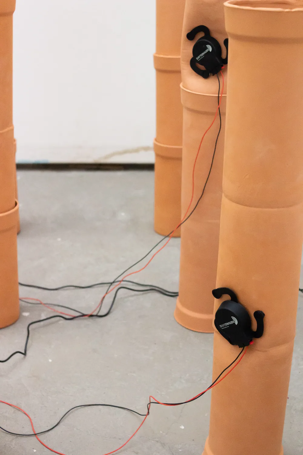 Nahaufnahme einiger nebeneinander aufgereihter Rohre mit befestigten Audio-Excitern.