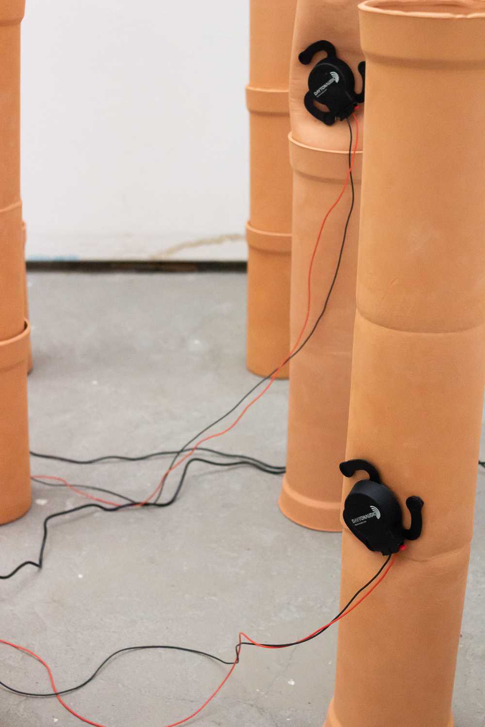 Nahaufnahme einiger nebeneinander aufgereihter Rohre mit befestigten Audio-Excitern.