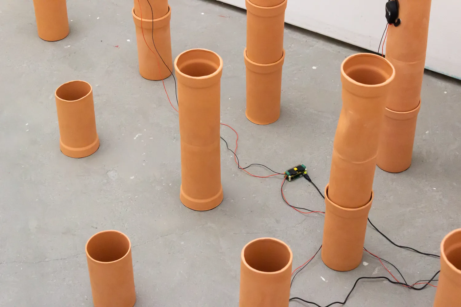 Vogelperspektive auf die Anordnung der Keramikrohre, die die in ein kleines elektronisches Gerät auf dem Boden führenden Drähte zeigt.