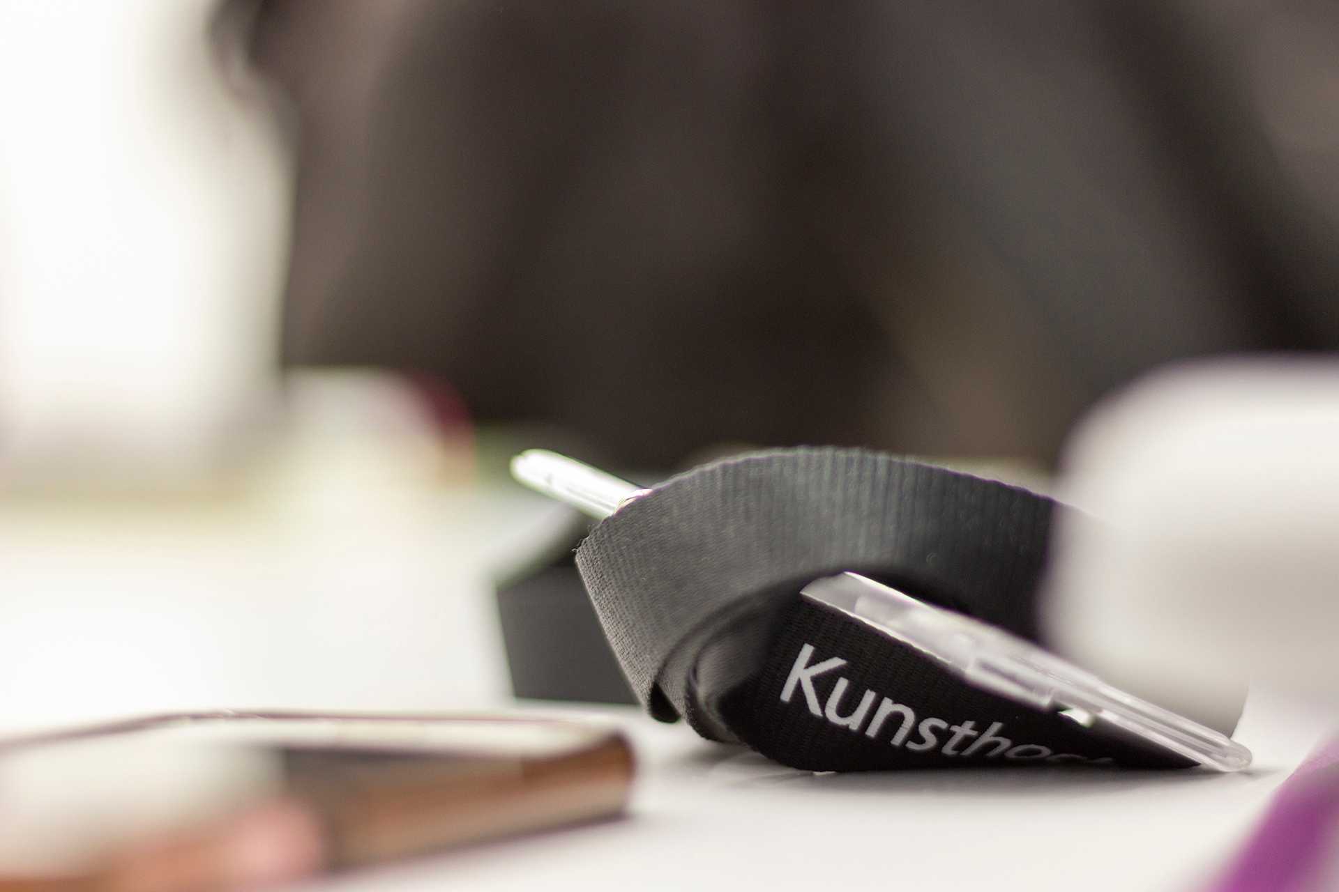 A lanyard sitting curled up on a table in a way such that the only word visible on it is 'Kunst'